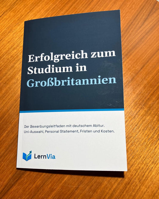 Taschenbuch „Erfolgreich zum Studium in Großbritannien“ von LernVia auf einem Holztisch